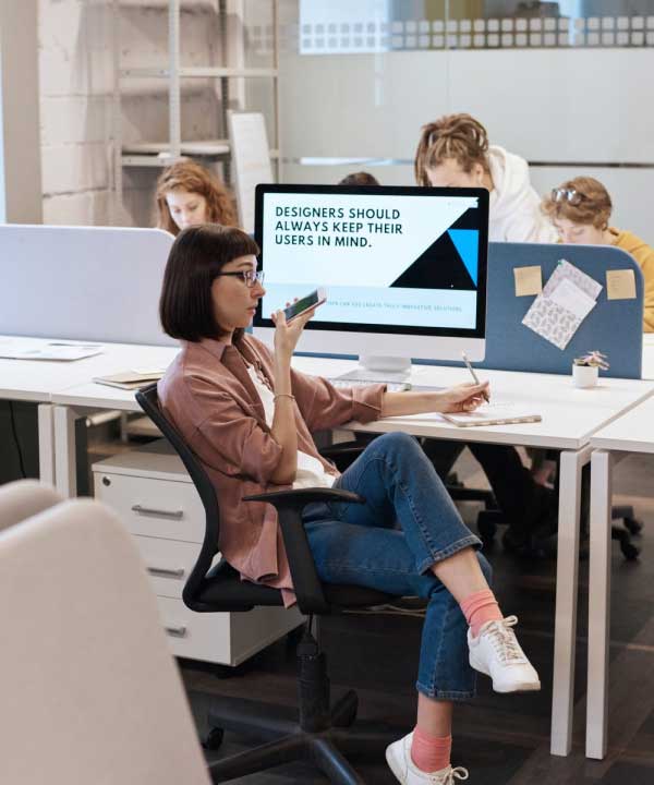 women speaking into a microphone while seated at a desk in a modern office workspace.